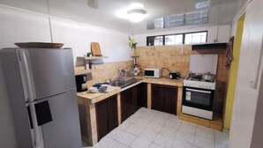 A compact kitchen with a refrigerator, microwave, stove, and sink. - Entire 2-bedroom townhouse (Saint-Denis)
