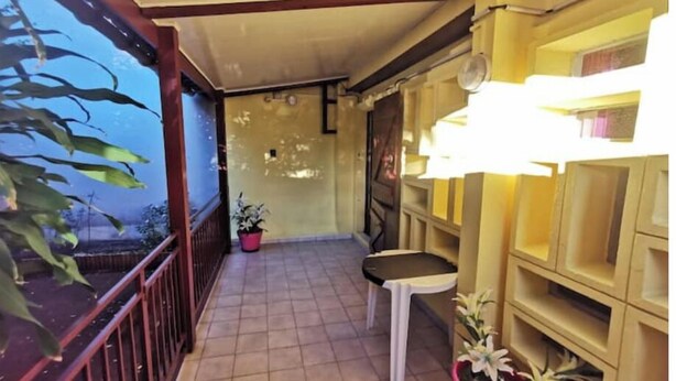 A covered balcony with tiled flooring, potted plants, and a small table. - Entire 2-bedroom townhouse (Saint-Denis)