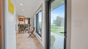 A modern kitchen with a dining area and large windows. - Modern PEI Shipping Container Retreat with Multiple Decks & Stunning Views (Oyster Bed Bridge)