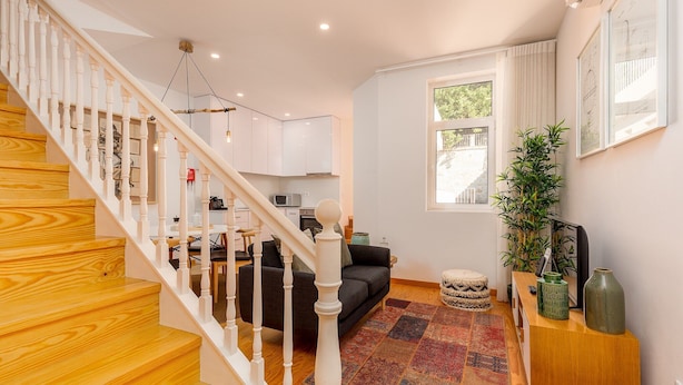 A modern living room with a staircase, a sofa, a coffee table, and a large window. - Charming Apartment in Oporto (Oporto)