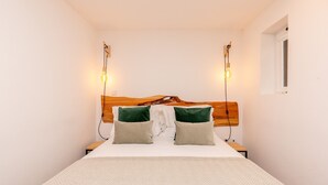 A neatly made bed with a wooden headboard, two bedside tables, and two wall-mounted reading lights. - Charming Apartment in Oporto (Oporto)