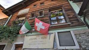Un edificio de madera con un letrero que dice "ANTICA STAZIONE DI POSTA" y banderas de Italia y Suiza.