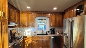 A modern kitchen with wooden cabinets, stainless steel appliances, and a tiled floor. - Welcome to our home! Lakefront Living, Where Beautiful Sunsets are unforgettable (Lake Park)