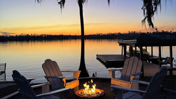 A lakeside deck with Adirondack chairs, a fire pit, and a gazebo. - Welcome to our home! Lakefront Living, Where Beautiful Sunsets are unforgettable (Lake Park)
