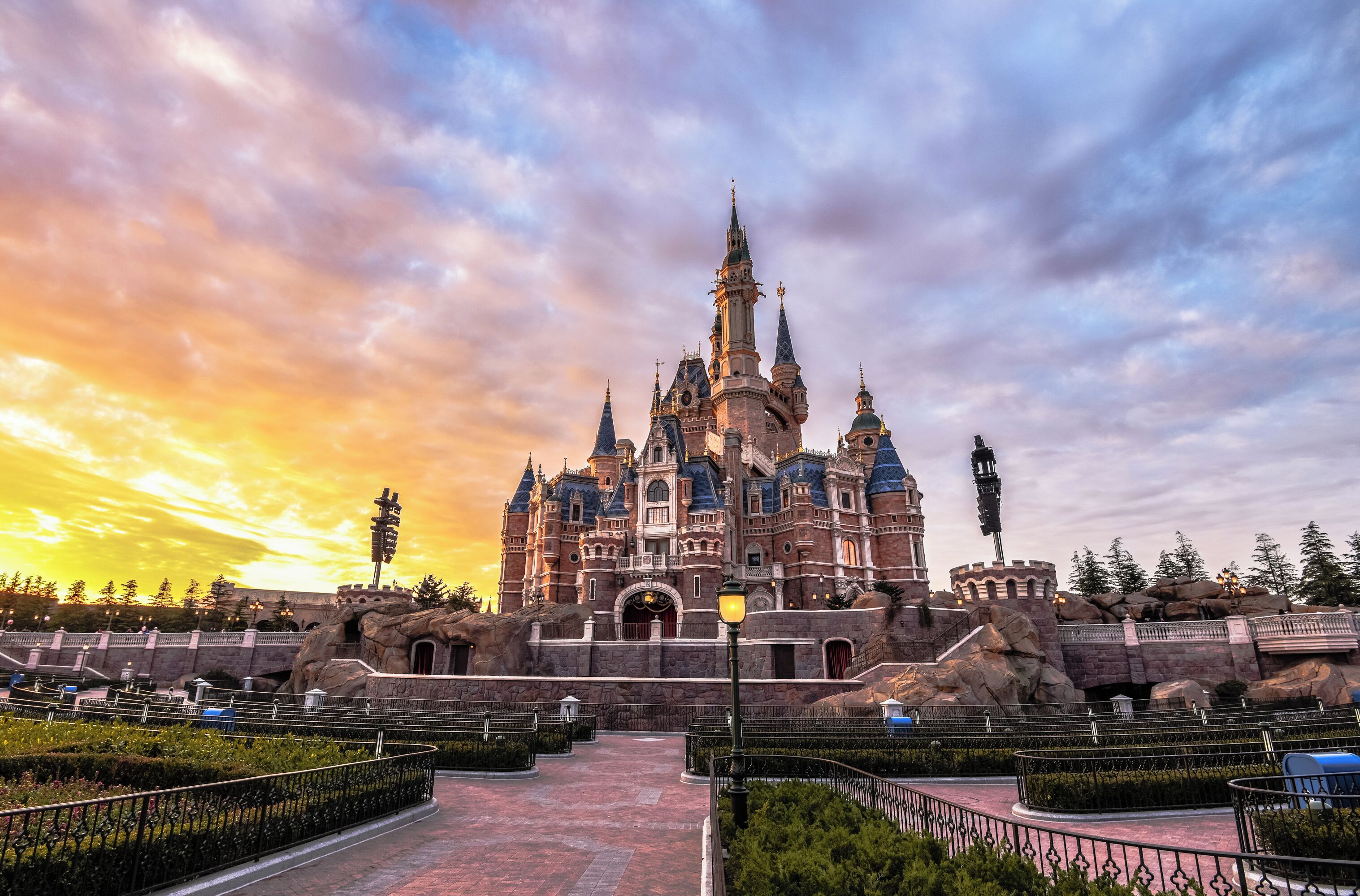 A grand castle-like building with multiple towers and a central entrance, surrounded by landscaped gardens and pathways.