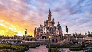 A grand castle-like building with multiple towers and a central entrance, surrounded by landscaped gardens and pathways.
