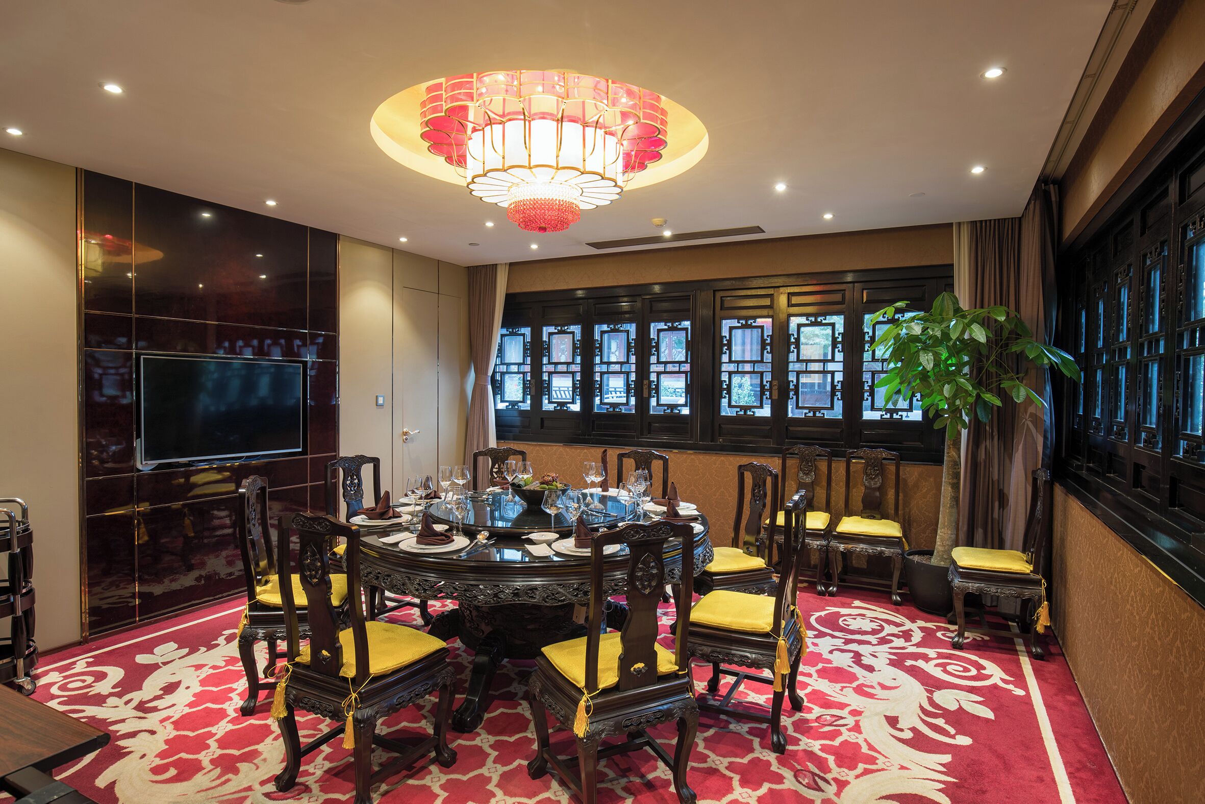 A dining area with a round table, chairs, and a chandelier.