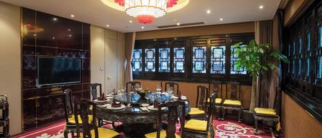 A dining area with a round table, chairs, and a chandelier.