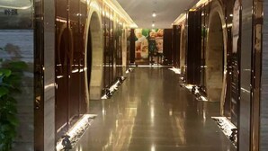 Un pasillo con suelo reflectante y puertas abovedadas que dan a habitaciones.