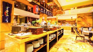 Zona de buffet con un chef, variedad de platos y ambiente bien iluminado.