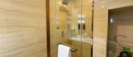 Een moderne badkamer met een douchecabine van glas, een glazen scherm en een wastafel met spiegel en handdoekhouder.