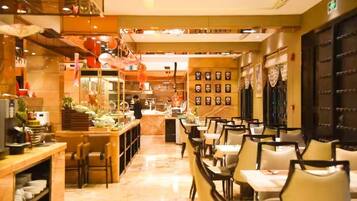 Un restaurante con una barra larga, varias mesas y sillas. Hay elementos decorativos y una persona trabajando detrás de la barra.