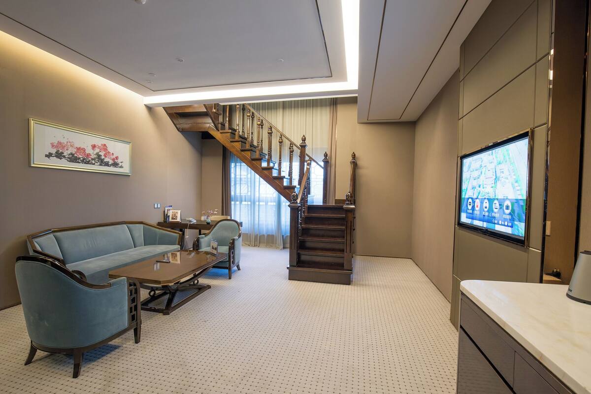 Un salon moderne comprenant un canapé, un fauteuil, une table basse et un escalier menant à un autre niveau.