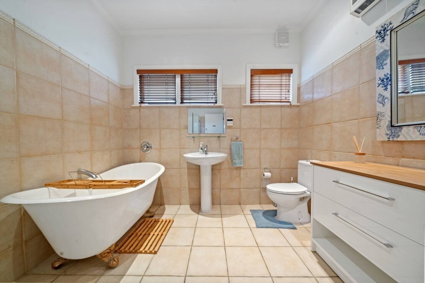A bathroom with a freestanding bathtub, a pedestal sink, a toilet, and a vanity with drawers.