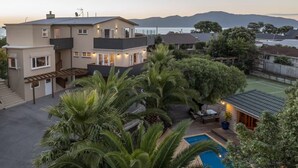 Ein zweistöckiges Haus mit Swimmingpool, umgeben von üppiger Vegetation und Blick auf das Meer.