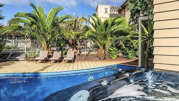 Ein Pool mit Whirlpool, umgeben von Palmen und Liegestühlen.