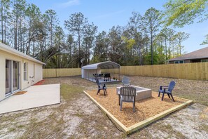 Un jardin avec un patio couvert, un espace salon extérieur et un foyer.