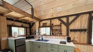 Una cocina con vigas de madera, un fregadero, un microondas y una cafetera.