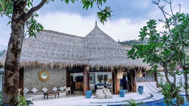 Un bâtiment à toit de chaume doté d’une piscine, d’un espace extérieur aménagé et offrant une vue sur le paysage environnant.