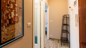 A narrow hallway with a wooden floor, a door leading to another room, and a black metal shelf against the wall. - Maurizio's Place by Interhome (Ceriale)