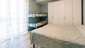 A bedroom with a bunk bed, a wardrobe, and a bed with a patterned bedspread. - Maurizio's Place by Interhome (Ceriale)