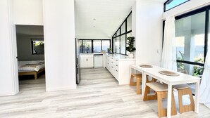 Uma cozinha moderna com armários brancos, uma ilha central e um espaço de refeições com banquetas.