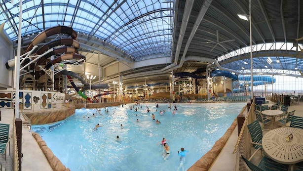 Una piscina interior con múltiples carriles, techo de cristal y varias toboganes de agua.