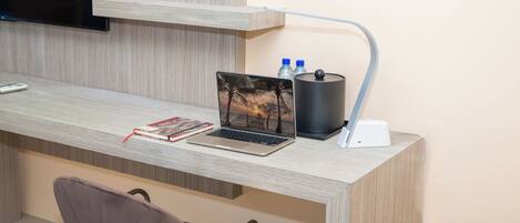 Un escritorio moderno con una computadora portátil, una botella de agua y una cafetera.