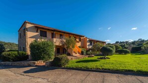 A two-story house with a stone facade, a balcony, and a well-maintained lawn. - Sea & Tranquility - with Wi-Fi and sea view (Olbia)