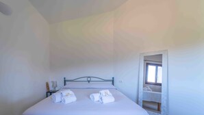 A single bed with neatly folded towels, a bedside table with a lamp, and a window with a view of a balcony. - Sea & Tranquility - with Wi-Fi and sea view (Olbia)