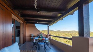A covered outdoor patio with a table and chairs, a view of the countryside, and a wooden ceiling. - Sea & Tranquility - with Wi-Fi and sea view (Olbia)