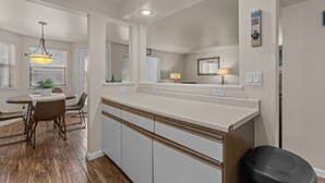 A modern kitchen with a central island, wooden cabinets, and a dining area with a table and chairs. - Boise's Lost Treasure (Boise)