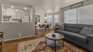 A modern living room with a gray sofa, a coffee table, and a dining area with a table and chairs. - Boise's Lost Treasure (Boise)