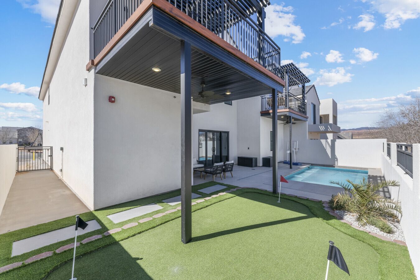 A modern two-story house with a covered patio, a swimming pool, and a well-maintained lawn.