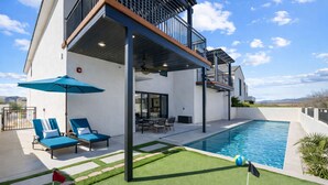 A modern house with a swimming pool, outdoor seating, and a covered patio area.