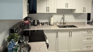 Una cucina moderna con mobili bianchi, un piano di lavoro in granito, forno integrato e lavello in acciaio inossidabile.