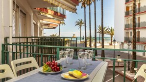 A balcony with a table set for two, featuring a plate of fruit and a plate of pastries.