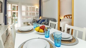 A dining area with a table set for two, a bowl of fruit, and blue glasses.