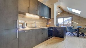 A modern kitchen with dark cabinets, a wooden countertop, and a skylight.