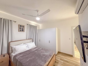 A bedroom with a bed, a wardrobe, a ceiling fan, and an air conditioning unit. - Hillside Condo - 2BR Charming APT Close to Strip! (Sosúa)