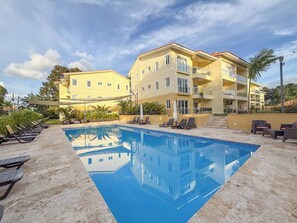 A hotel with a swimming pool, multiple balconies, and outdoor seating areas.