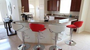 Een moderne keuken met een centraal eiland, barkrukken en houten kastjes.
