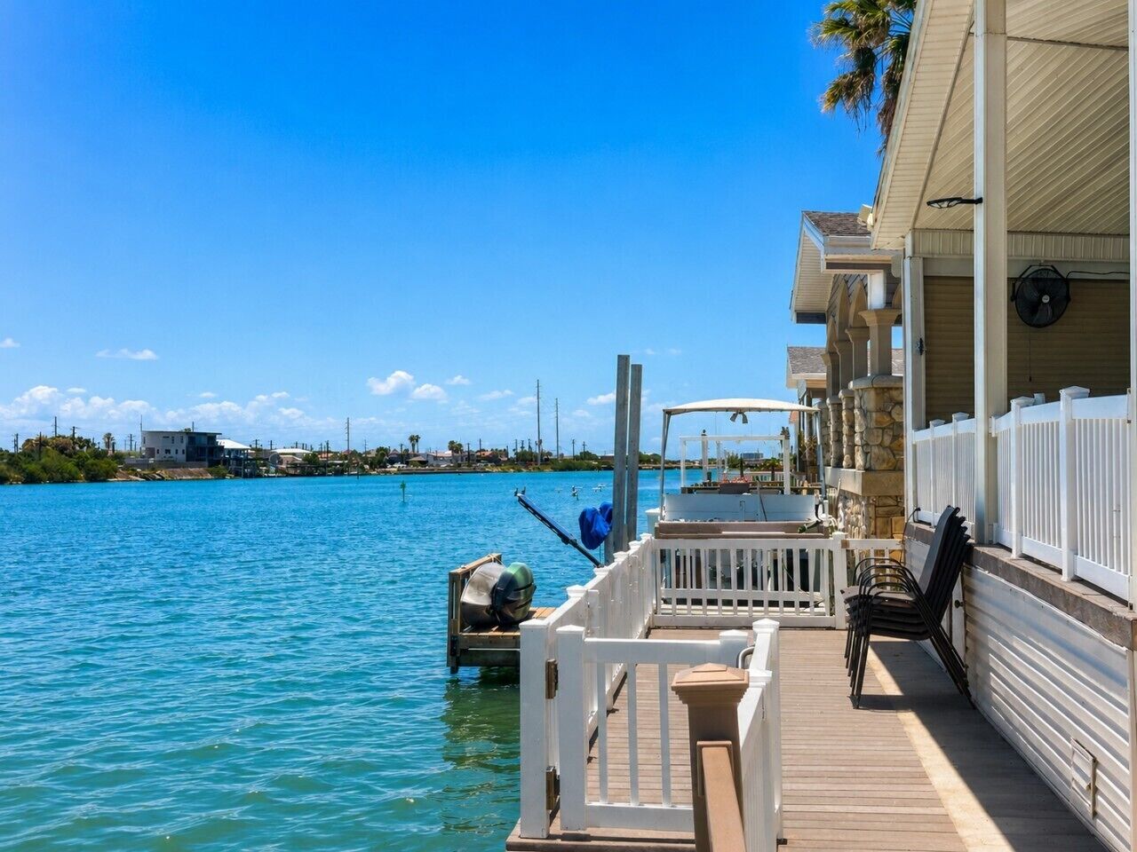 A waterfront property with a dock, a covered area with chairs, and a view of the water.
