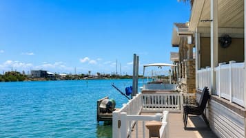 A waterfront property with a dock, a covered area with chairs, and a view of the water.