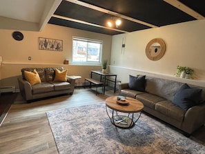 A living room with a sofa, coffee table, and a dining area.