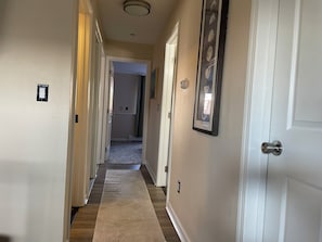A hallway with a carpet, a door, and a wall-mounted picture frame.