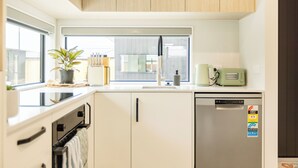 A modern kitchen with a built-in oven, a refrigerator, and a window with a view. - Brand New 3BR Home with Parking in Christchurch (Tristate)