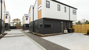 A modern residential building with a flat roof, large windows, and a concrete driveway. - Brand New 3BR Home with Parking in Christchurch (Tristate)