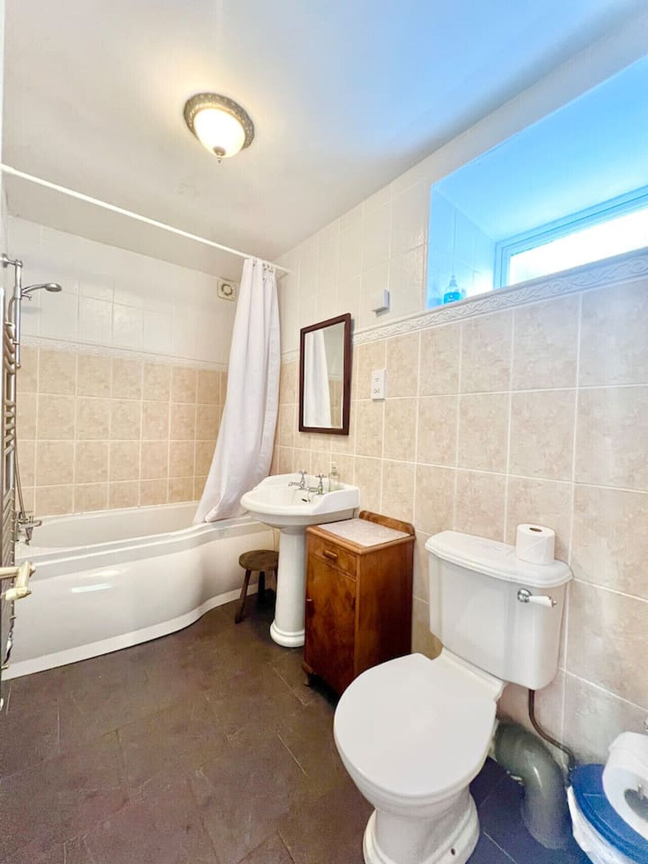 Een badkamer met een bad, een wastafel, een toilet en een spiegel.