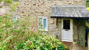 A stone house with a sloped roof, a small porch, and a window. - Coach House Quiet Country Retreat for 6 Near Coast (Loddiswell)
